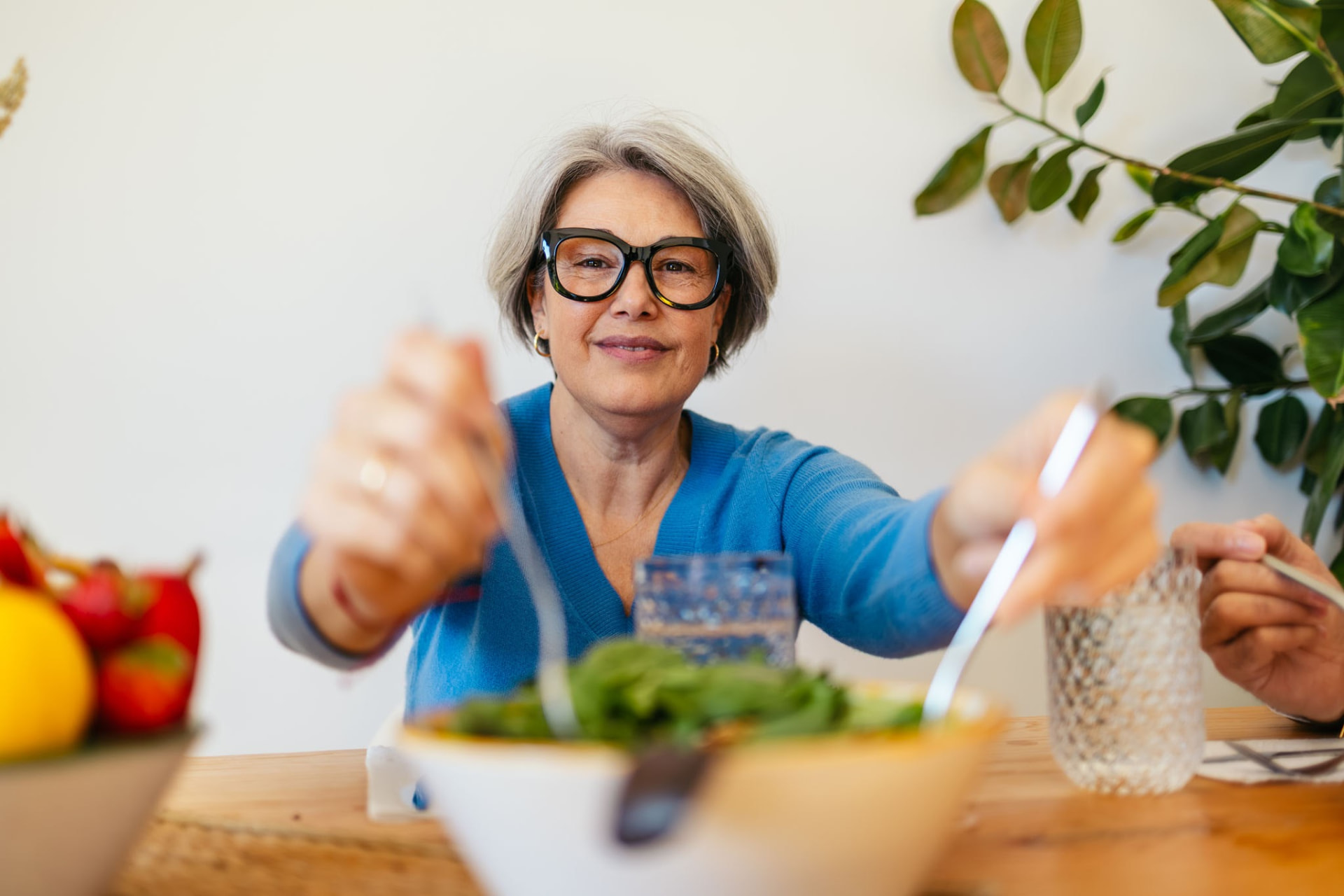 Woman in her 60s with glasses enjoying a fresh green salad